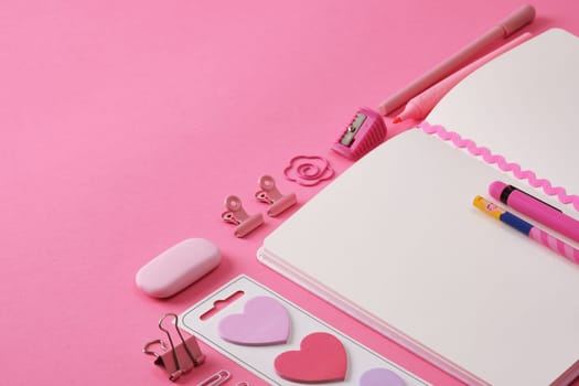 Stationery background in pink color, open notepad and office supplies. A place for your text.