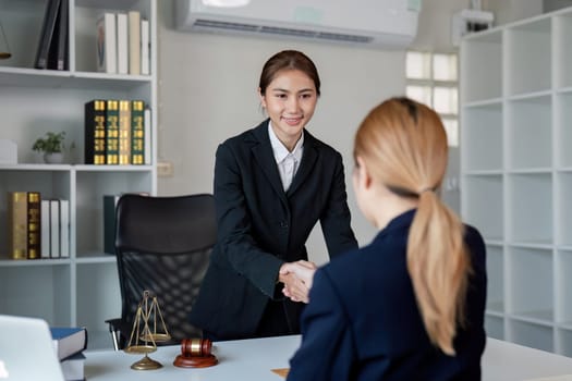 A lawyer smiling and shaking hands with a client, symbolizing successful collaboration and agreement after a thorough legal consultation in a contemporary office setting.