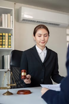A focused lawyer holding a gavel and discussing a contract with a client, showcasing professionalism and legal expertise in an office environment.