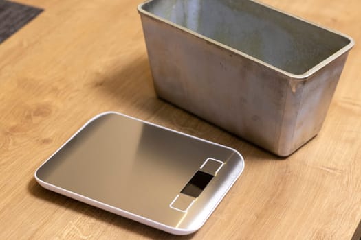 Small electronic scale on the kitchen counter top beside with the bread loaf pan