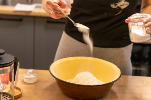 Woman adding ingredients together to prepare dough