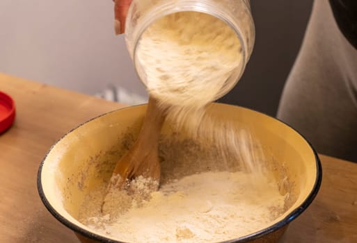 Woman adding ingredients together to prepare dough
