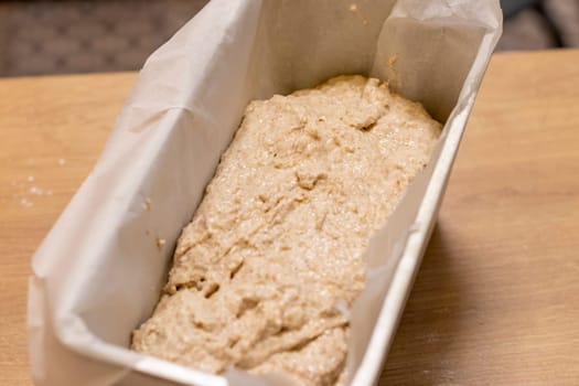 Close up shot of the bread loaf pan with the dough on the kitchen counter top