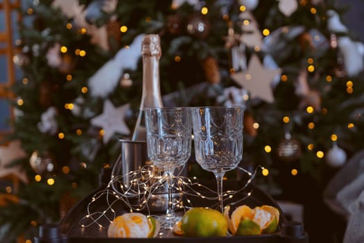 Champagne glasses, New Year decor. New Year's festive setting, family holidays.Two glasses of champagne are on the table against the background of New Year's decorated tree