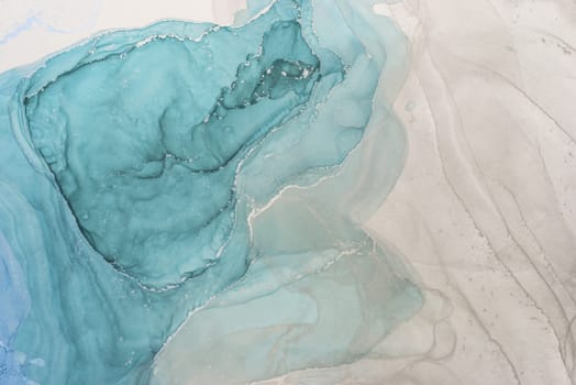 Flowing layers of alcohol ink create an abstract art piece characterized by soothing blue tones set against a light background.
