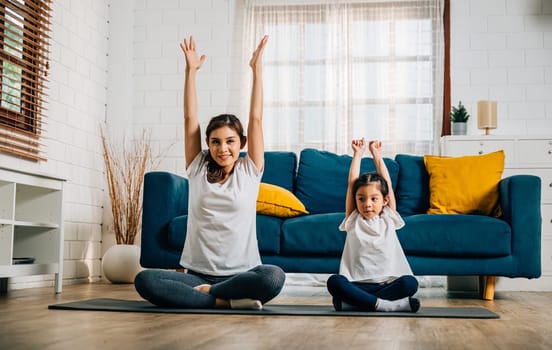 In their cozy home a mother and her delightful daughter practice family yoga embracing smiles as they stretch and balance together fostering togetherness and happiness.
