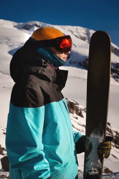 Close up portrait of a guy holding skis in winter, sportswear, winter holidays in nature, traveling on ski slopes.