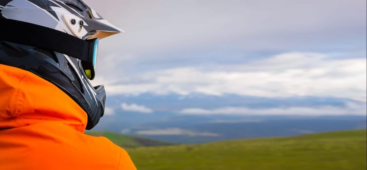 portrait of a cyclist or motorcyclist on top of a mountain, viewed from the back, looking at the mountain range in the clouds. panoramic mountain view, sport and banner concept for advertising.