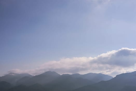 Mountain peaks with clouds in sunny skies. Fog, empty space, blue mystery, light, soft