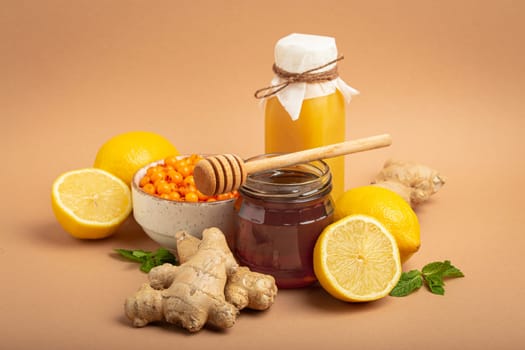 Composition with detox drink, sea buckthorn berries, lemons, mint, ginger, honey in glass jar. Food for immunity stimulation and against flu. Healthy natural remedies to boost immune system.