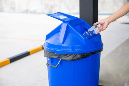 Close up woman hand throwing empty plastic water bottle into recycling bin, female throwing empty bottle to trash, Recycle rubbish, save the world and environment care