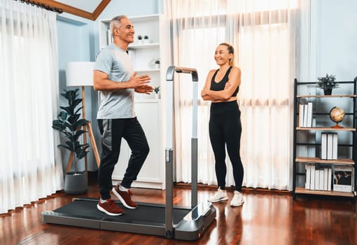 Active senior couple running on tread running machine at home together in full body shot as fitness healthy lifestyle and body care after retirement for pensioner. Clout