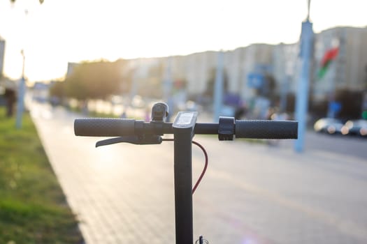 Electric scooter against the background of the city at sunset close up