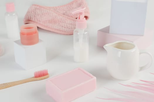 Skincare routine. Pink Women skincare products on white background. Soap, facial foam, cleansing, serum, cream lotion, toothbrush, lipstick. Beauty concept. Natural cosmetic pink flat lay top view.