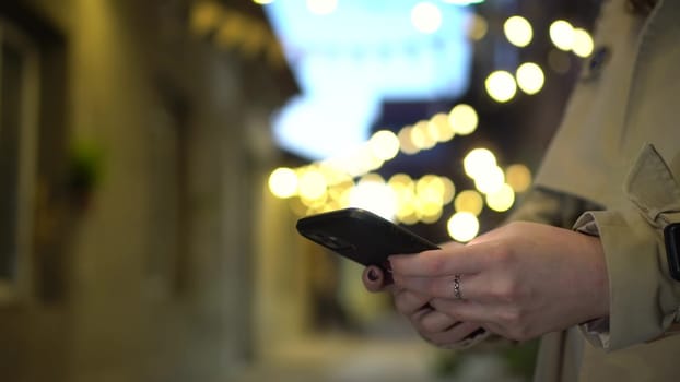 A girl chats on her smartphone late at night on the street. Close-up phone. 4k