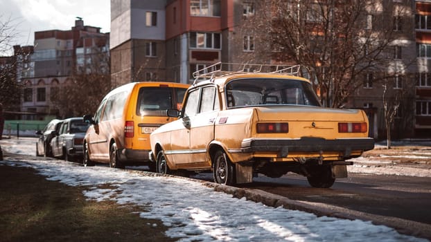 An old yellow Soviet car in the courtyard of a residential building. High quality photo