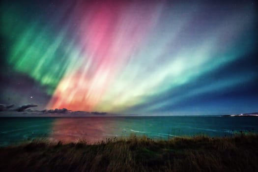 The ethereal Aurora Borealis lights up the night sky over the St. Abbs coastline in the UK. Shades of green and pink illuminate the scene, blending seamlessly with the dark, starry sky and reflecting on the ocean below. A captivating and serene depiction of the natural beauty of the northern lights, ideal for travel, nature, and celestial themes.