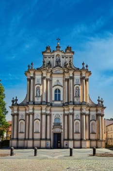A stunning photograph of the Church of St. Casimir in Warsaw, Poland. The Baroque-style architecture stands tall under a clear blue sky, featuring intricate details and symmetry. Ideal for cultural, religious, and architectural photography