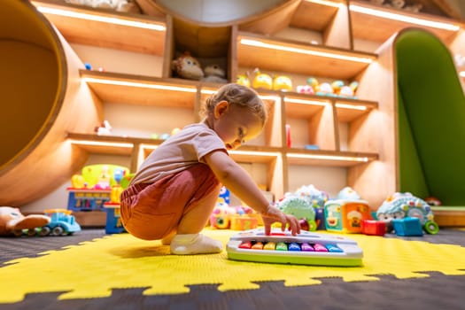 Child developing motor skills while playing with a musical toy in a bright playroom