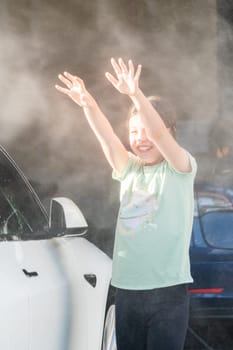 A young girl enthusiastically assists in washing the family's electric car in their suburban driveway.