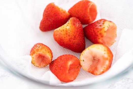 Freshly washed and dried strawberries are carefully arranged in a glass bowl lined with paper towel, ready for snacking or further use.
