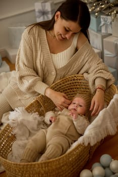 A woman holding a baby.The girl holds her child in her arms. The child is wearing a beige hand-knitted hat. mother and child are happy, they are smiling. They celebrate Christmas.