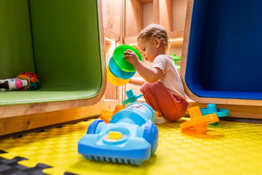 Child exploring activity toys and shelves in a vibrant indoor playroom for creative playtime