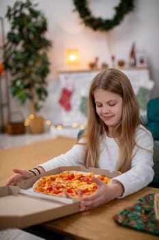 A cheerful and joyful child eagerly opens a pizza box in a warm, festive setting filled with vibrant holiday decor