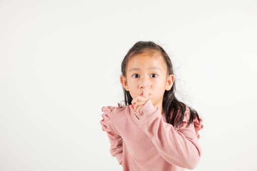Young kid girl making finger on lips mouth silent quiet gesture, Happy Asian kindergarten child marking silence for stop quiet, mute studio shot isolated on white background with copy space