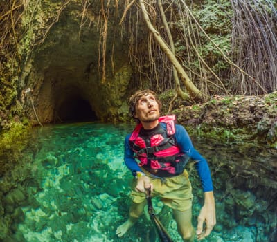 09.12.24, Playa Del Carmen, Mexico: Man tourist standing in the water of a cenote at Xcaret park wearing a marked life jacket. Mexican tourism in natural parks. Adventure, relaxation, and eco-tourism concept in Quintana Roo.