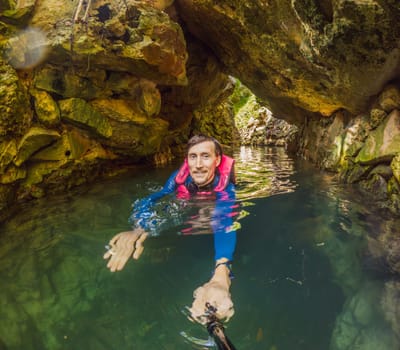 09.12.24, Playa Del Carmen, Mexico: Man tourist standing in the water of a cenote at Xcaret park wearing a marked life jacket. Mexican tourism in natural parks. Adventure, relaxation, and eco-tourism concept in Quintana Roo.