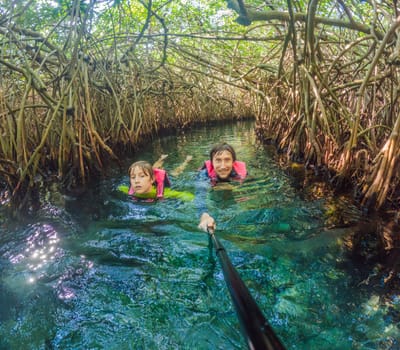 09.12.24, Playa Del Carmen, Mexico: Father and son tourists in the water of a cenote at Xcaret park wearing marked life jackets. Mexican tourism in natural parks. Family bonding, eco-tourism, and adventure concept in Quintana Roo.