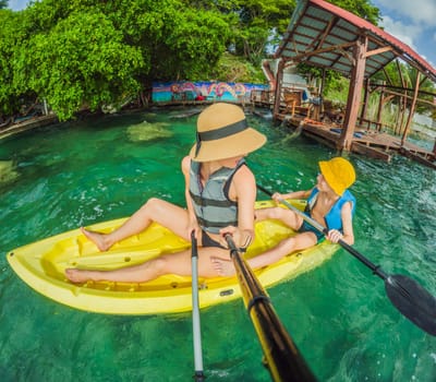 Mother and son tourists kayaking together on the crystal-clear turquoise waters of Lake Bacalar, Mexico. Family bonding, outdoor adventure, and tropical travel concept in a serene natural setting.
