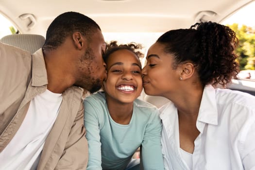 Cheerful Black Parents Kissing Daughter Sitting In New Car Riding Enjoying Road Trip Together. African American Family Having Summer Vacation And Traveling By Auto. Transportation Concept