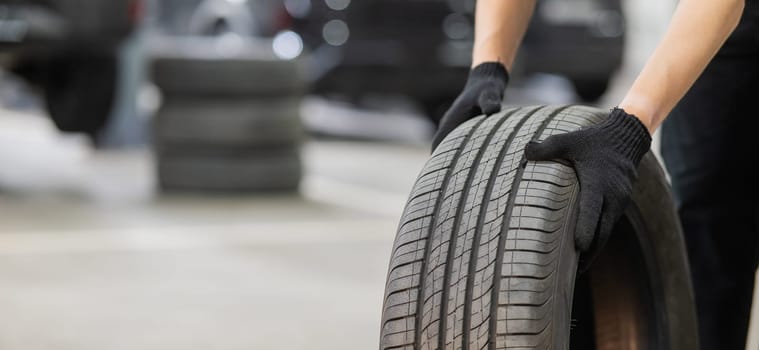 Man holding old car tire. Close up of mechanic's hands with wheel