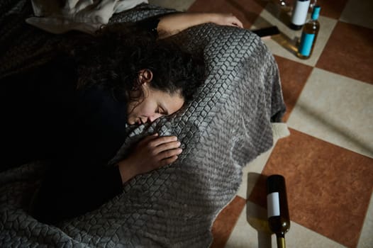 A person resting on the floor with surrounding empty bottles, depicting themes of overindulgence and reflection.