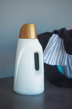 The image shows a closeup of a laundry detergent bottle next to a vibrant array of clothes