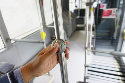 Close-up of a person holding a metal pole inside a public bus, emphasizing public transportation.
