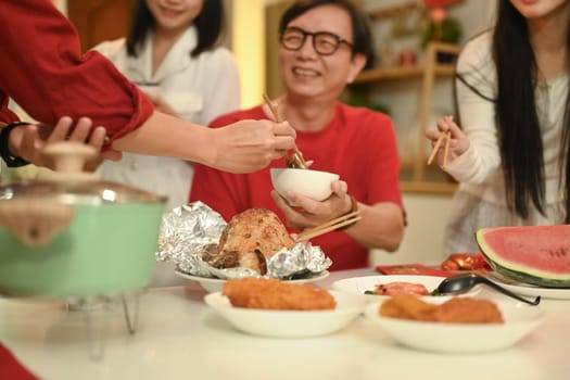 Chinese family sharing delicious food during Chinese New Year celebration in cozy home.