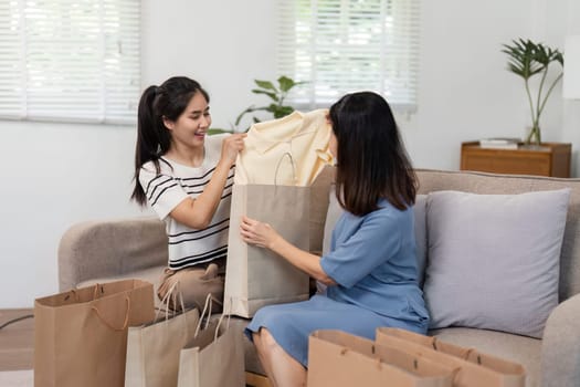A mother and child happily browse and shop for clothes online, enjoying quality time together in a comfortable home setting.