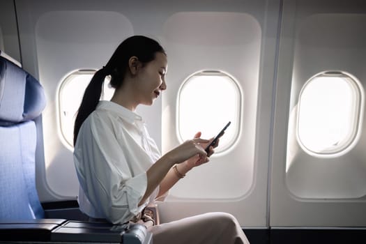 Businesswoman on a plane using a smartphone, showcasing modern travel and professional lifestyle.