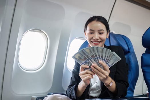 A confident businesswoman in a suit smiles while holding a fan of dollar bills, symbolizing financial success and achievement.