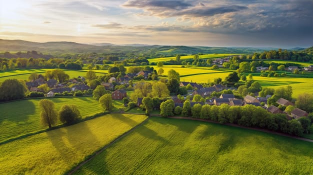 An expansive landscape captures a village nestled among rolling green fields, with golden sunlight illuminating the scenery as clouds drift overhead during sunset - Generative AI