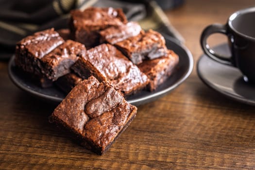 Homemade chocolate brownies on plate on a wooden table.