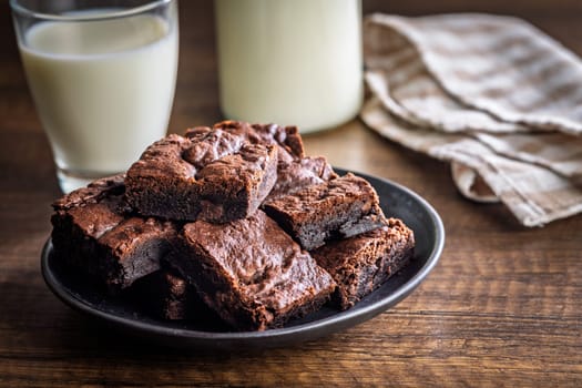 Homemade chocolate brownies on plate on a wooden table.