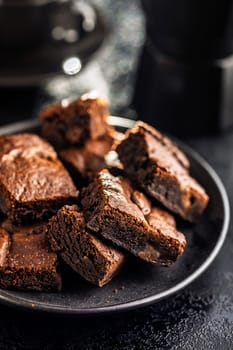 Homemade chocolate brownies on plate on a black table.