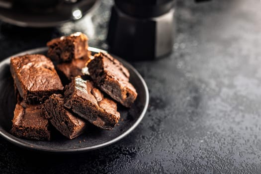 Homemade chocolate brownies on plate on a black table.