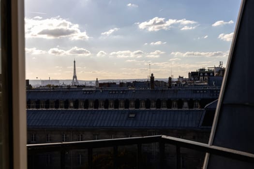 Open window with romantic view of rooftops and Eiffel Tower in Paris, France.