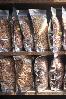 close up of many mixed nuts in packet at shelf .