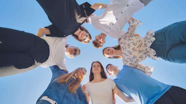 Seven young high school students amicably put their heads together and look down